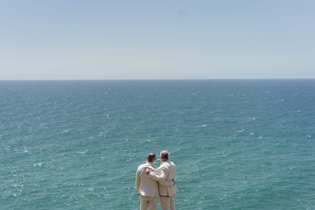 same sex couple just married and looking out to sea