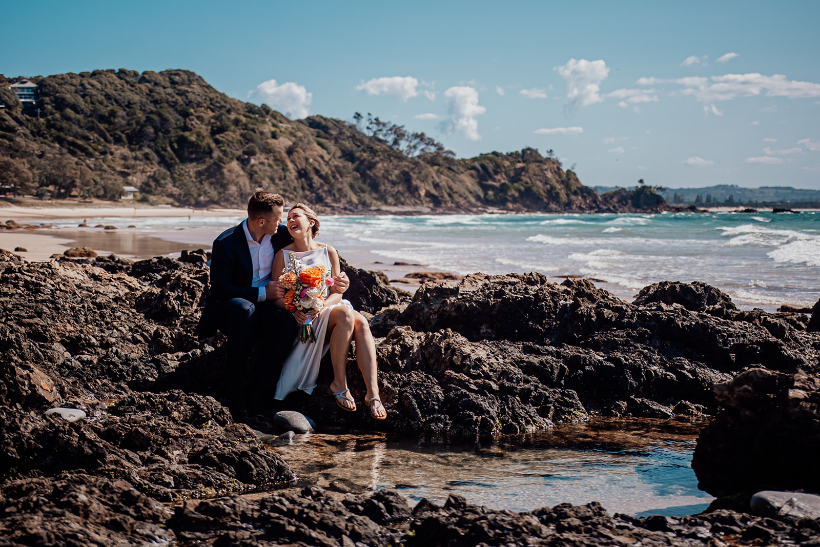 Bride and groom sharing a kiss at a rockpool on Wategos beach after their wedding